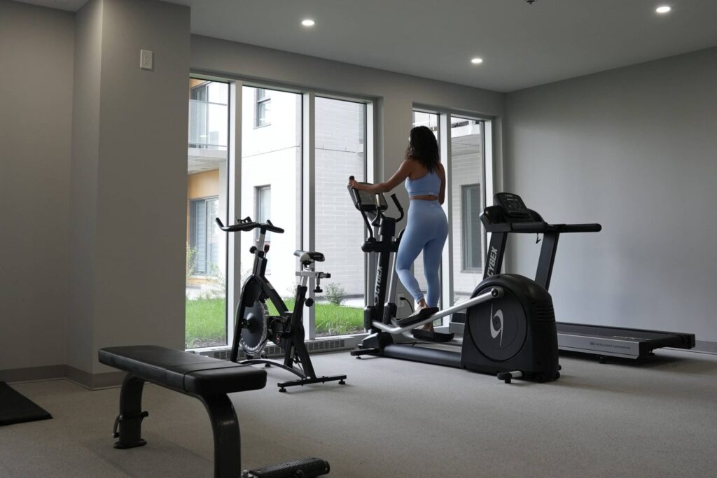 Femme s’entraînant dans la salle de sport du projet de condos locatifs Signature Bois-Franc, à Saint-Laurent, Montréal